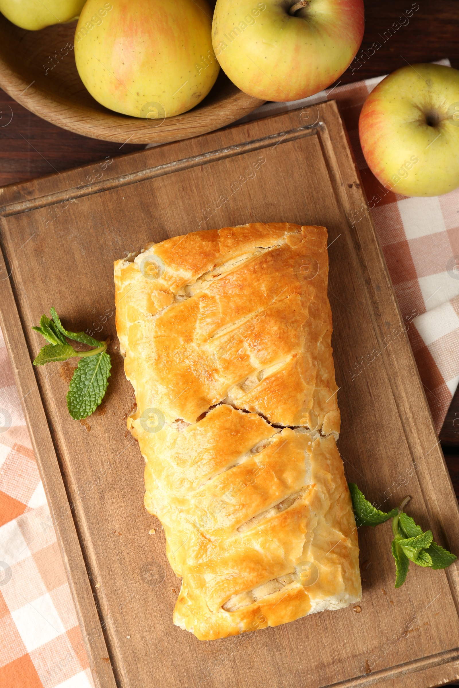 Photo of Delicious strudel with apples and mint on table, flat lay