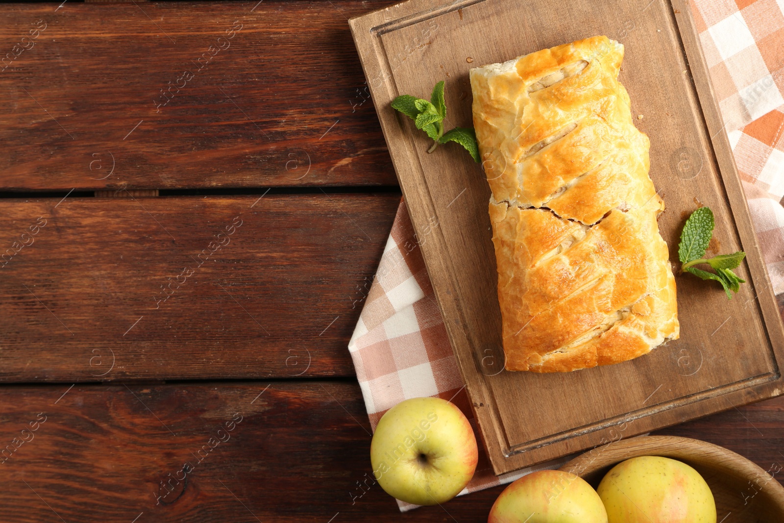 Photo of Delicious strudel with apples and mint on wooden table, flat lay. Space for text