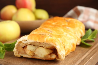 Photo of Delicious strudel with apples and mint on table, closeup