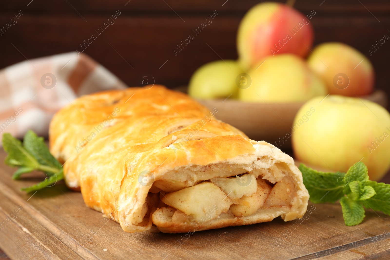 Photo of Delicious strudel with apples and mint on table, closeup