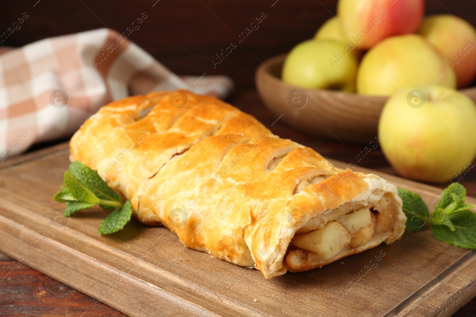 Photo of Delicious strudel with apples and mint on wooden table, closeup