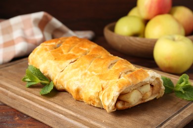 Delicious strudel with apples and mint on wooden table, closeup