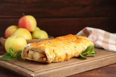 Photo of Delicious strudel with apples and mint on wooden table, closeup