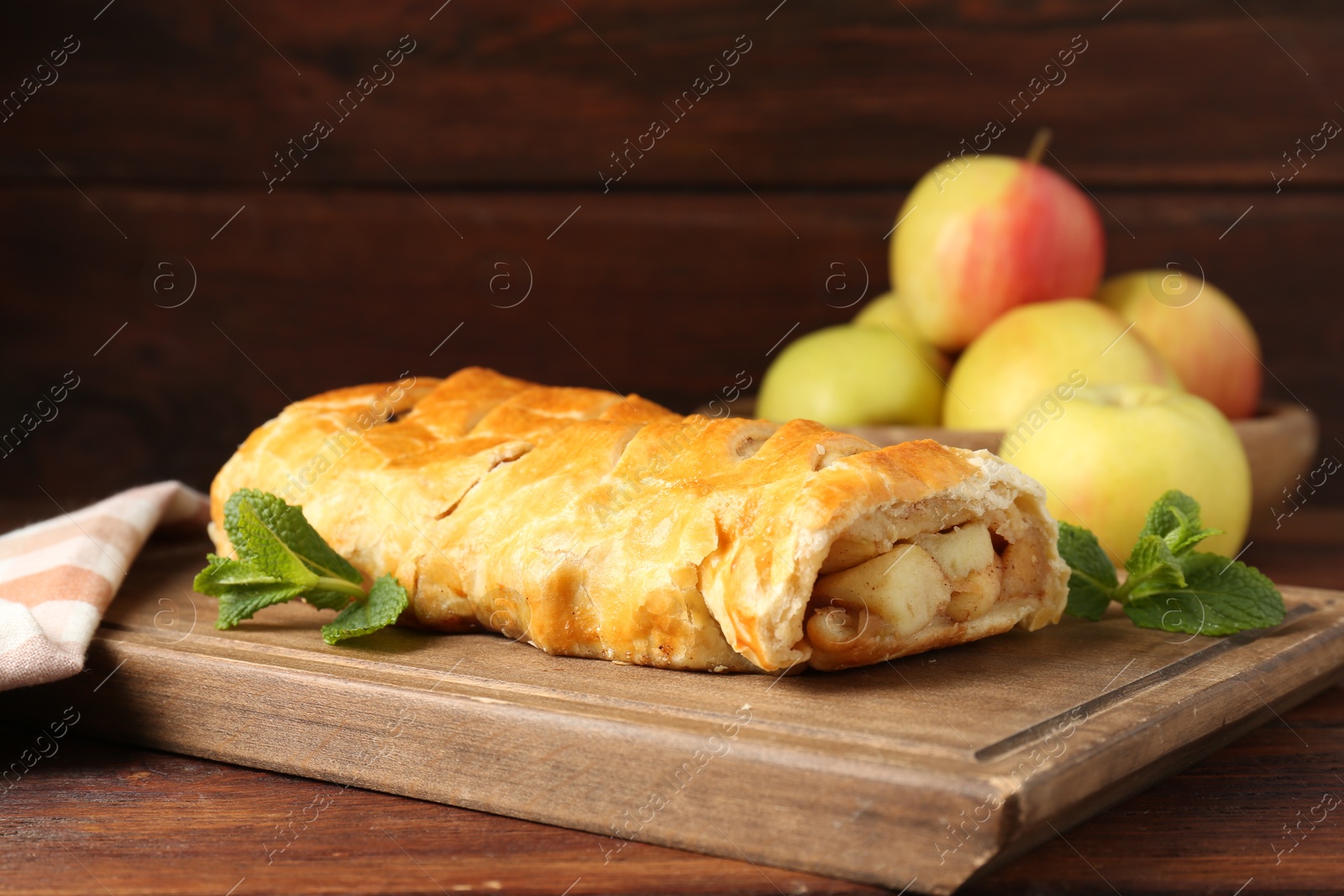 Photo of Delicious strudel with apples and mint on wooden table, closeup