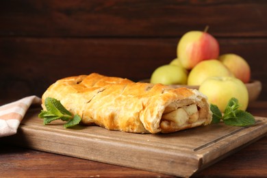 Delicious strudel with apples and mint on wooden table, closeup