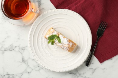 Photo of Piece of tasty apple strudel served with tea on white marble table, flat lay