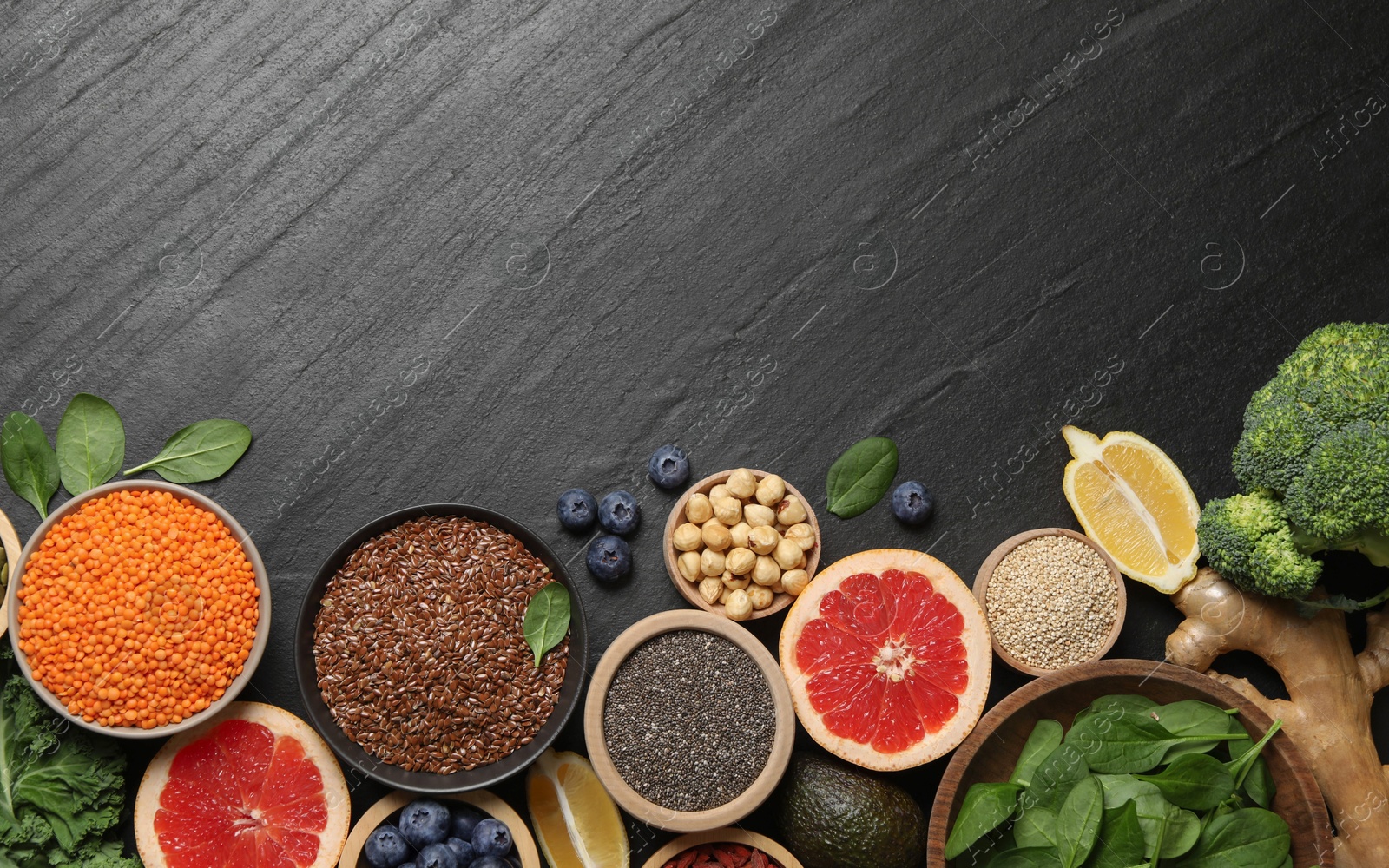 Photo of Different superfood products on black table, flat lay. Space for text