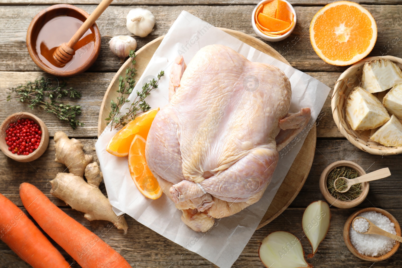 Photo of Uncooked turkey, orange slices, carrots and spices on wooden table, flat lay