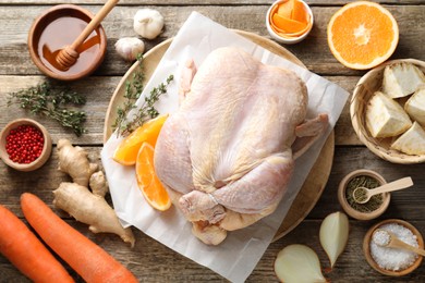 Uncooked turkey, orange slices, carrots and spices on wooden table, flat lay