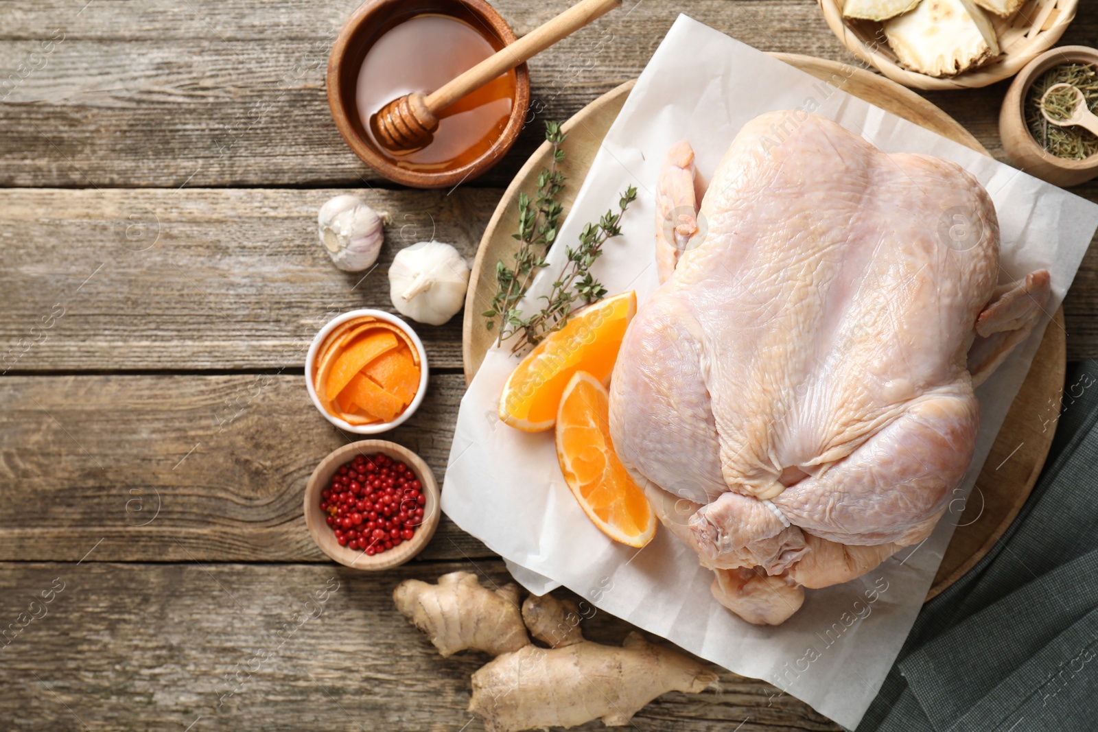 Photo of Uncooked turkey, orange slices and spices on wooden table, flat lay