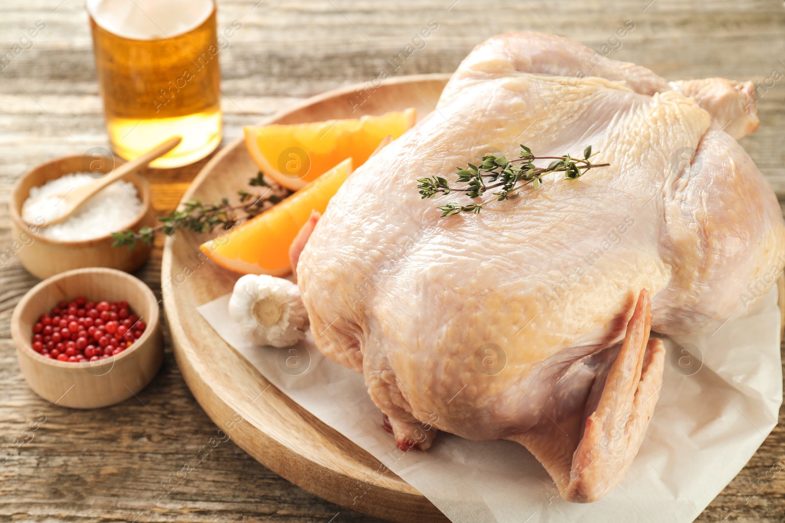 Photo of Uncooked turkey, orange slices and spices on wooden table, closeup