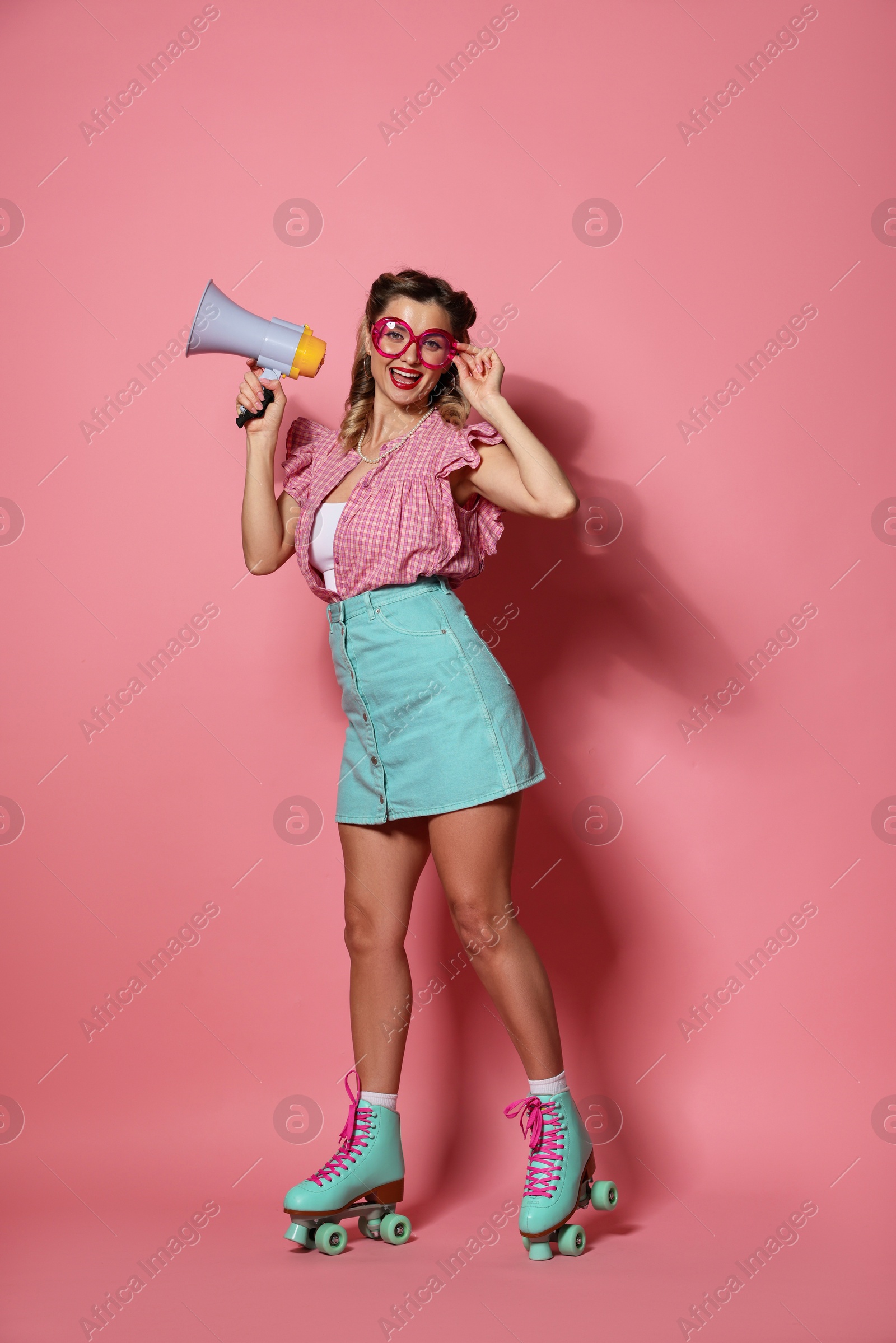 Photo of Happy pin-up woman with megaphone wearing roller skates on pink background