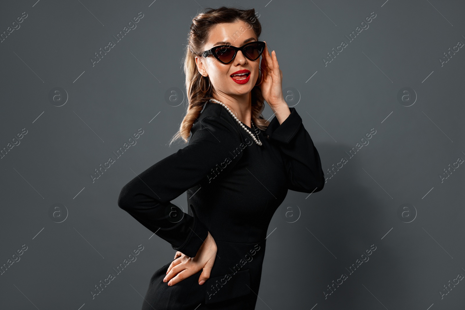 Photo of Beautiful woman in sunglasses on grey background. Pin-up vibe portrait