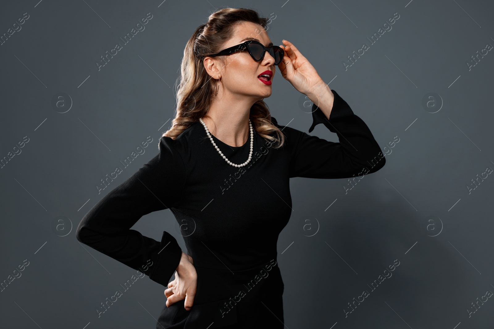 Photo of Beautiful woman in sunglasses on grey background. Pin-up vibe portrait