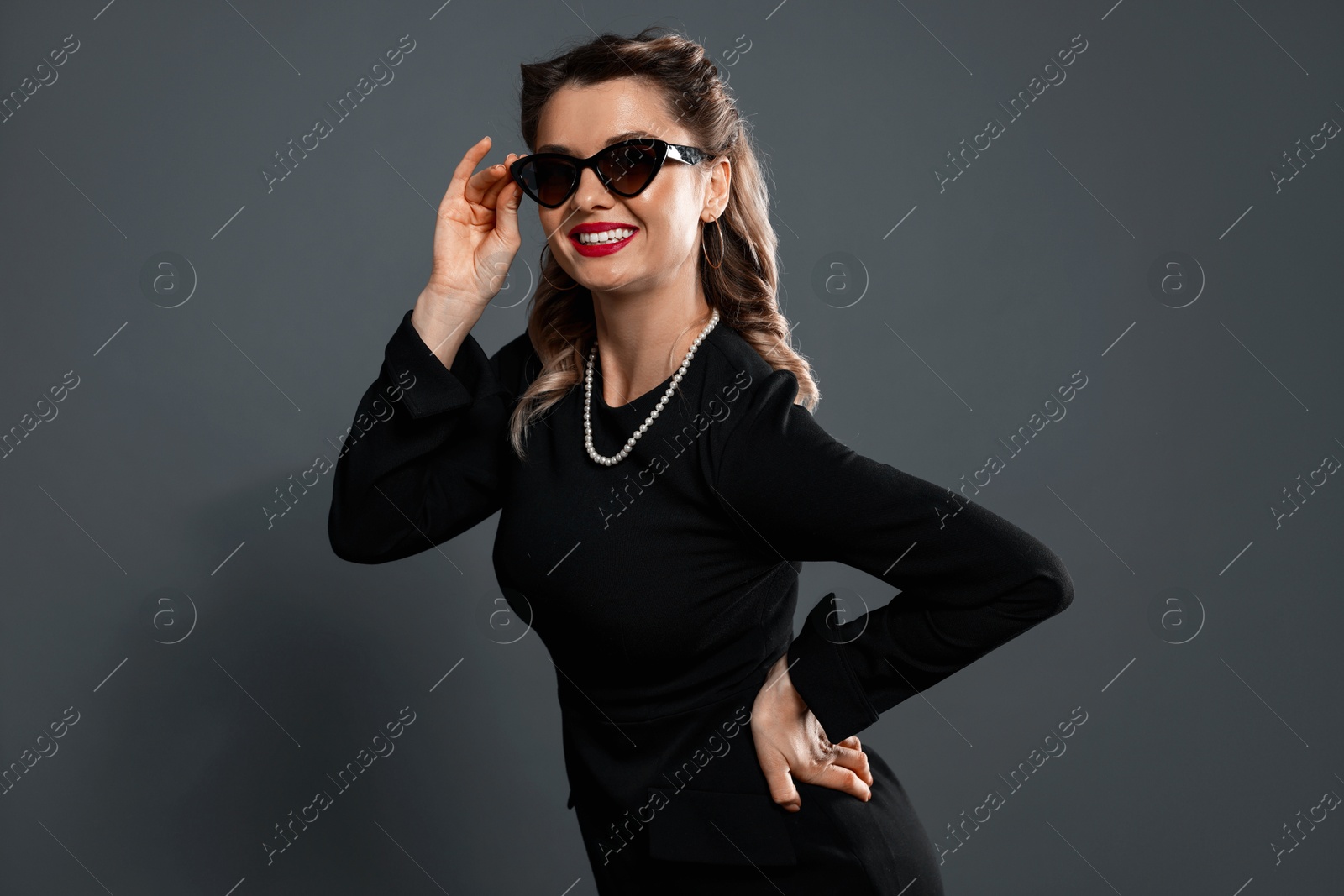 Photo of Happy woman in sunglasses on grey background. Pin-up vibe portrait