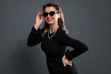 Photo of Happy woman in sunglasses on grey background. Pin-up vibe portrait