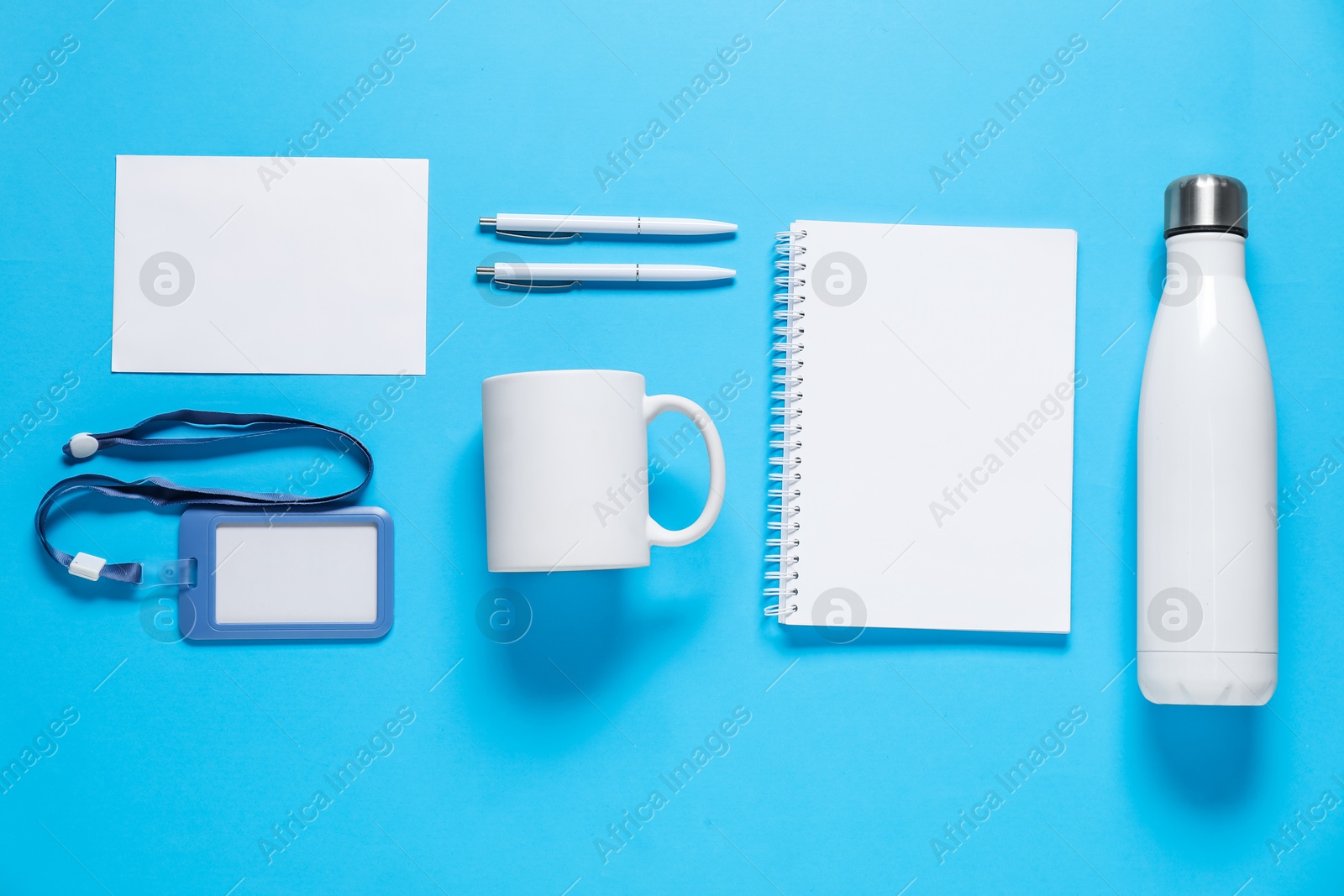 Photo of Different blank items for branding on light blue background, flat lay. Mockup for design