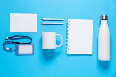 Photo of Different blank items for branding on light blue background, flat lay. Mockup for design