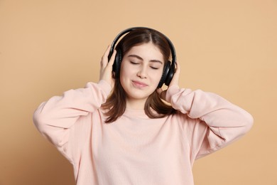 Photo of Portrait of teenage girl in headphones listening to music on beige background