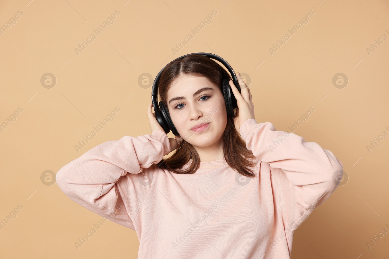 Photo of Portrait of teenage girl in headphones listening to music on beige background