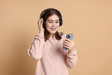 Photo of Portrait of teenage girl in headphones with smartphone on beige background