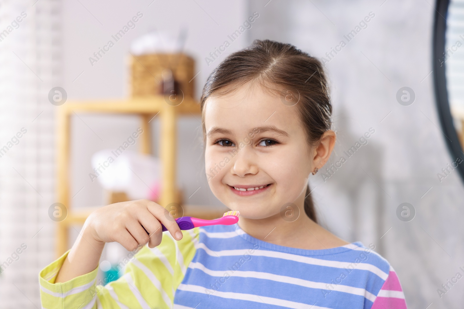 Photo of Cute girl with toothbrush in bathroom. Personal hygiene