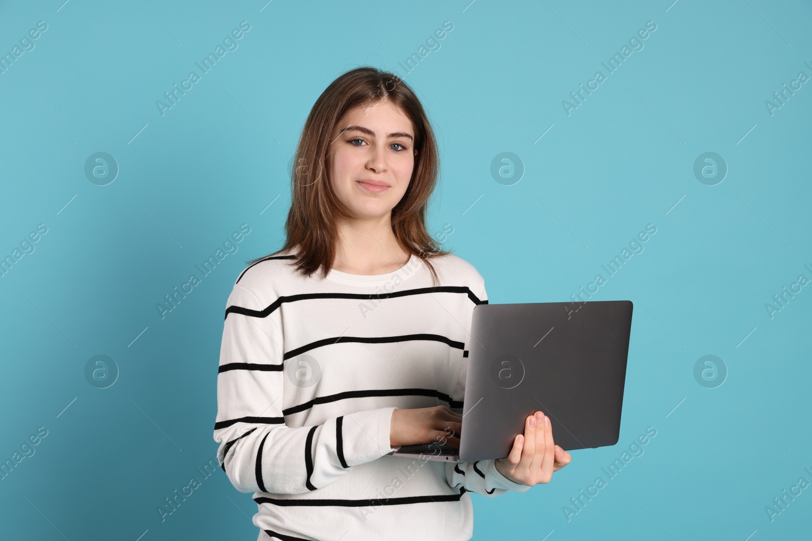 Photo of Portrait of teenage girl using laptop on light blue background