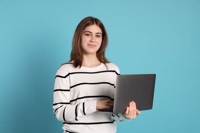 Photo of Portrait of teenage girl using laptop on light blue background