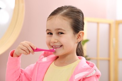 Photo of Cute girl brushing her teeth in bathroom