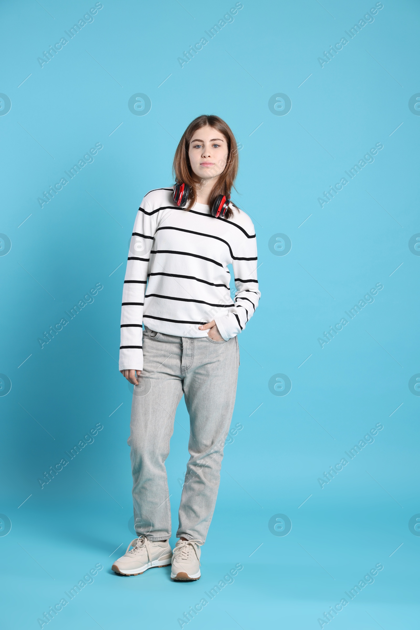 Photo of Teenage girl with headphones on light blue background