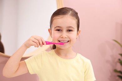 Photo of Cute girl brushing her teeth in bathroom