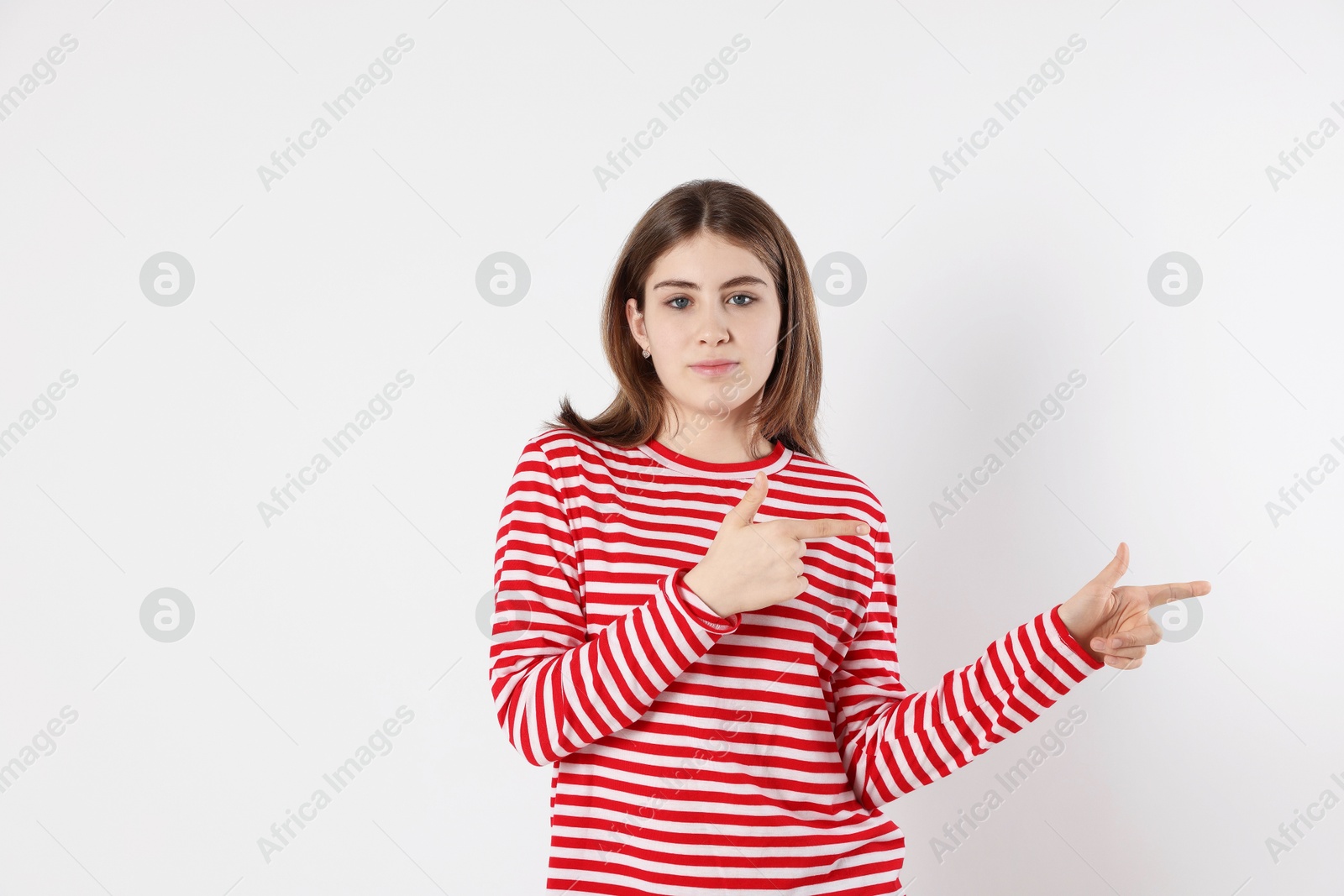 Photo of Portrait of teenage girl pointing at something on light background