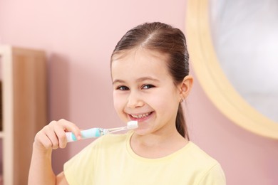 Photo of Cute girl brushing her teeth in bathroom