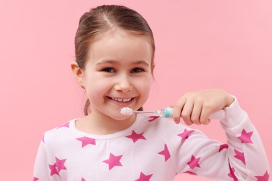 Photo of Cute girl brushing her teeth on pink background