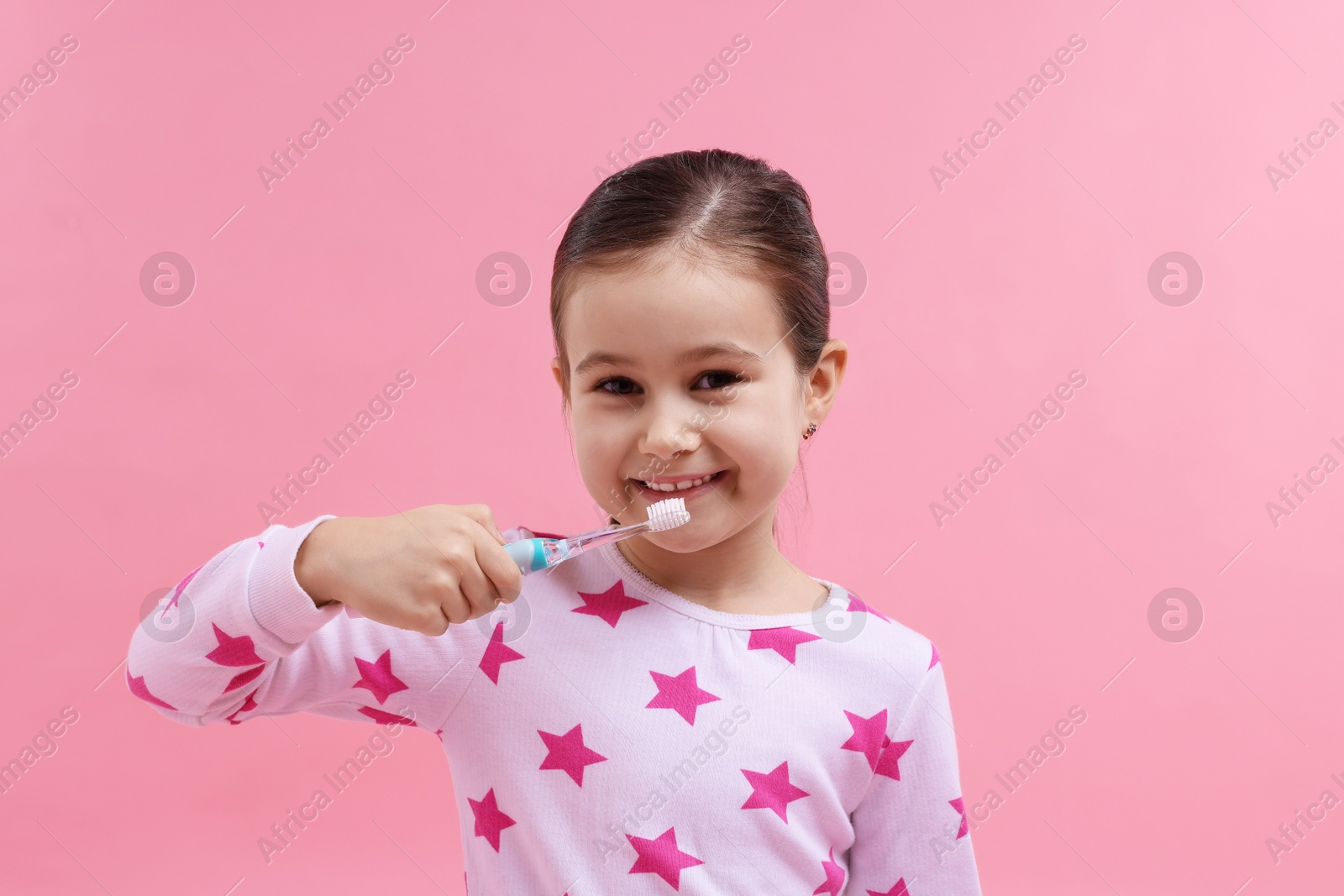 Photo of Cute girl brushing her teeth on pink background