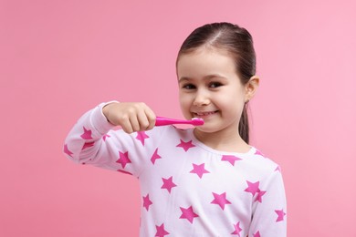 Photo of Cute girl brushing her teeth on pink background