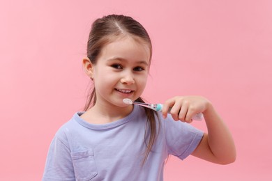 Photo of Cute girl with toothbrush on pink background