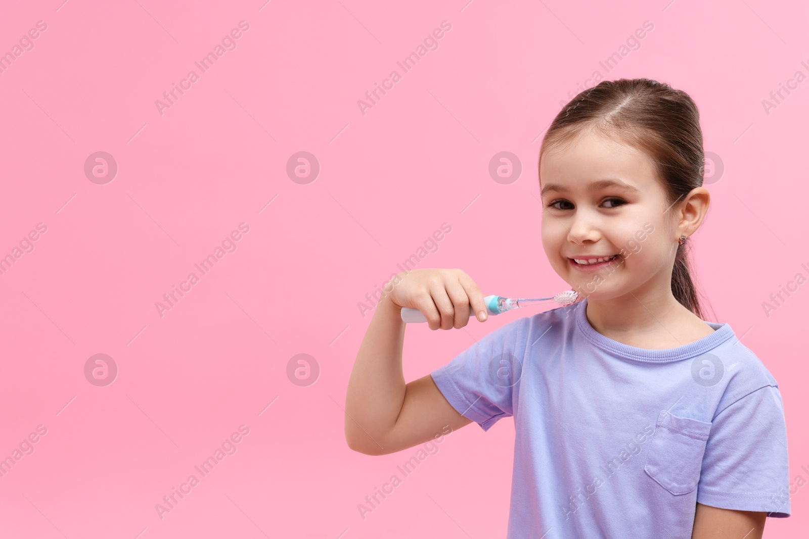 Photo of Cute girl with toothbrush on pink background, space for text