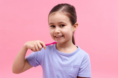 Photo of Cute girl with toothbrush on pink background