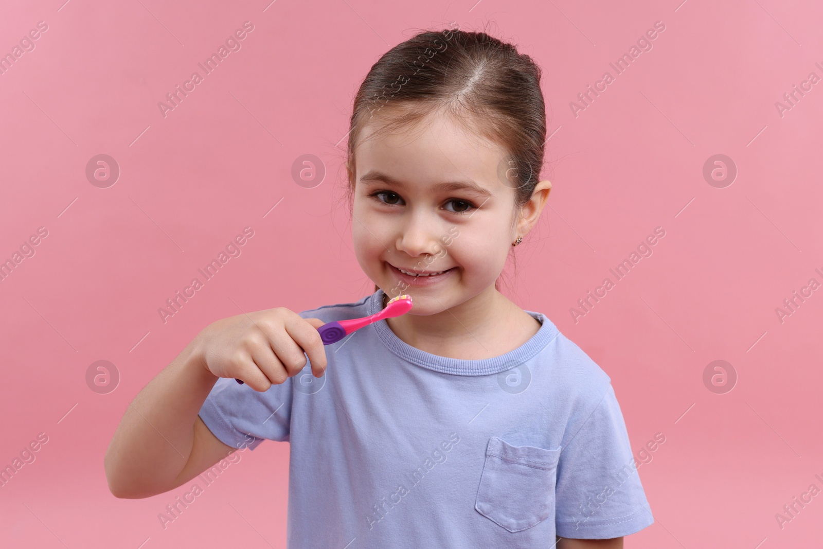 Photo of Cute girl with toothbrush on pink background