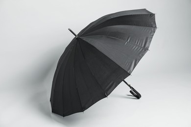 Photo of Open blank black parasol for branding on light grey background. Mockup for design