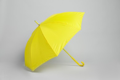 Photo of Open blank yellow parasol for branding on light grey background. Mockup for design