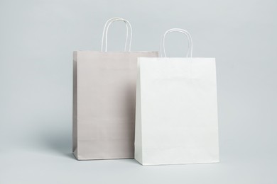 Photo of Two blank shopping bags on light grey background. Mockup for design