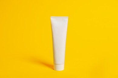 Photo of Blank tube of cosmetic product for branding on orange background. Mockup for design