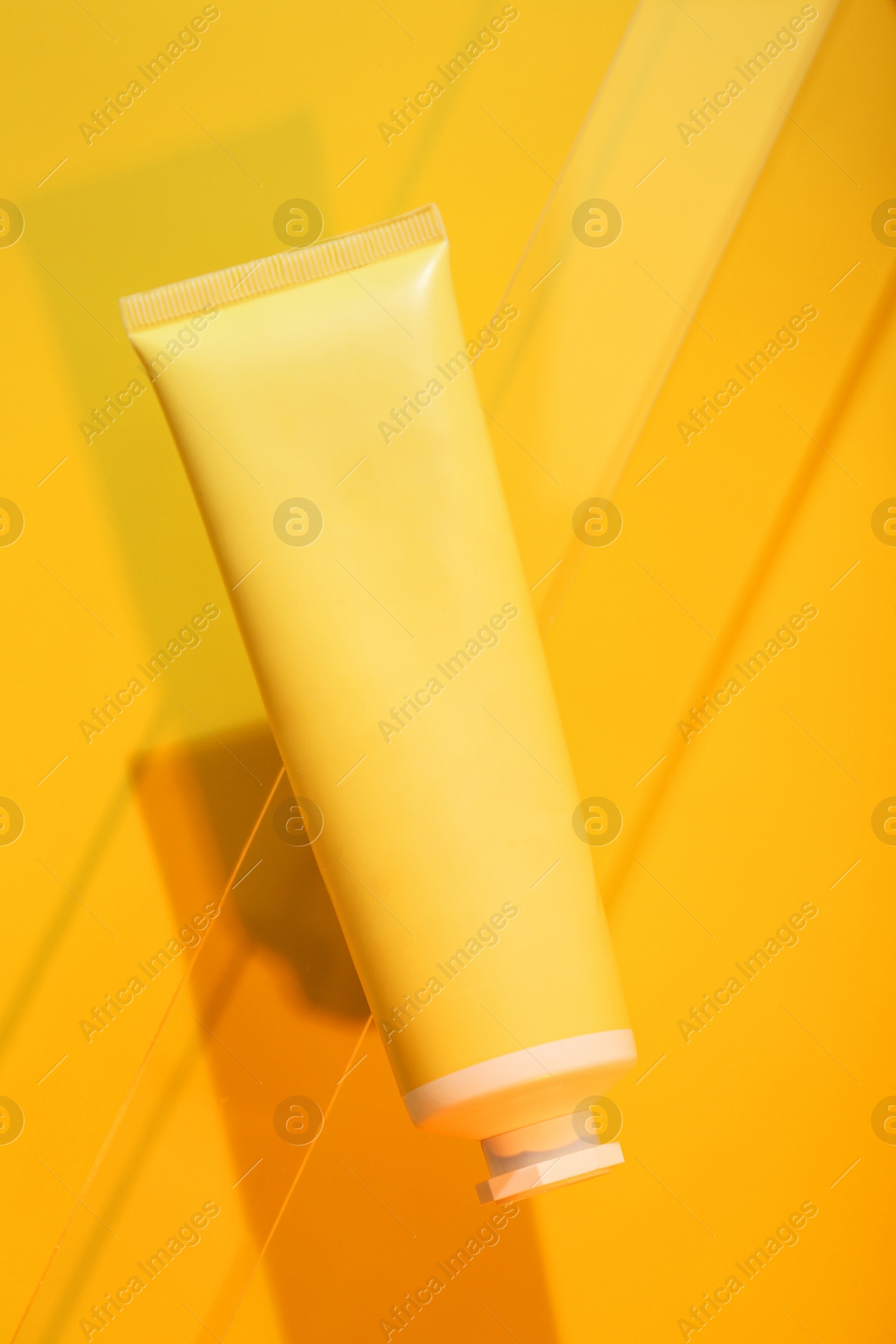 Photo of Tube of cream on orange background, top view. Stylish presentation of skincare product