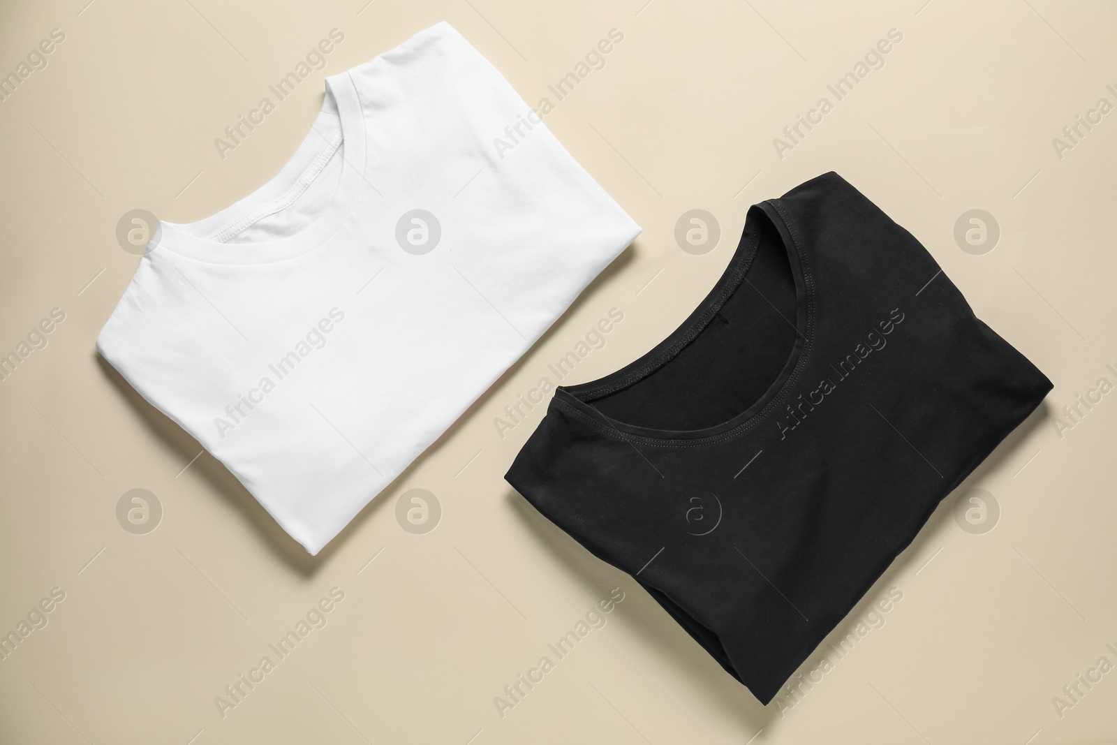 Photo of Two blank t-shirts on beige background, flat lay. Mockup for design