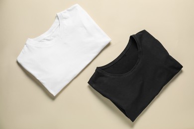 Photo of Two blank t-shirts on beige background, flat lay. Mockup for design