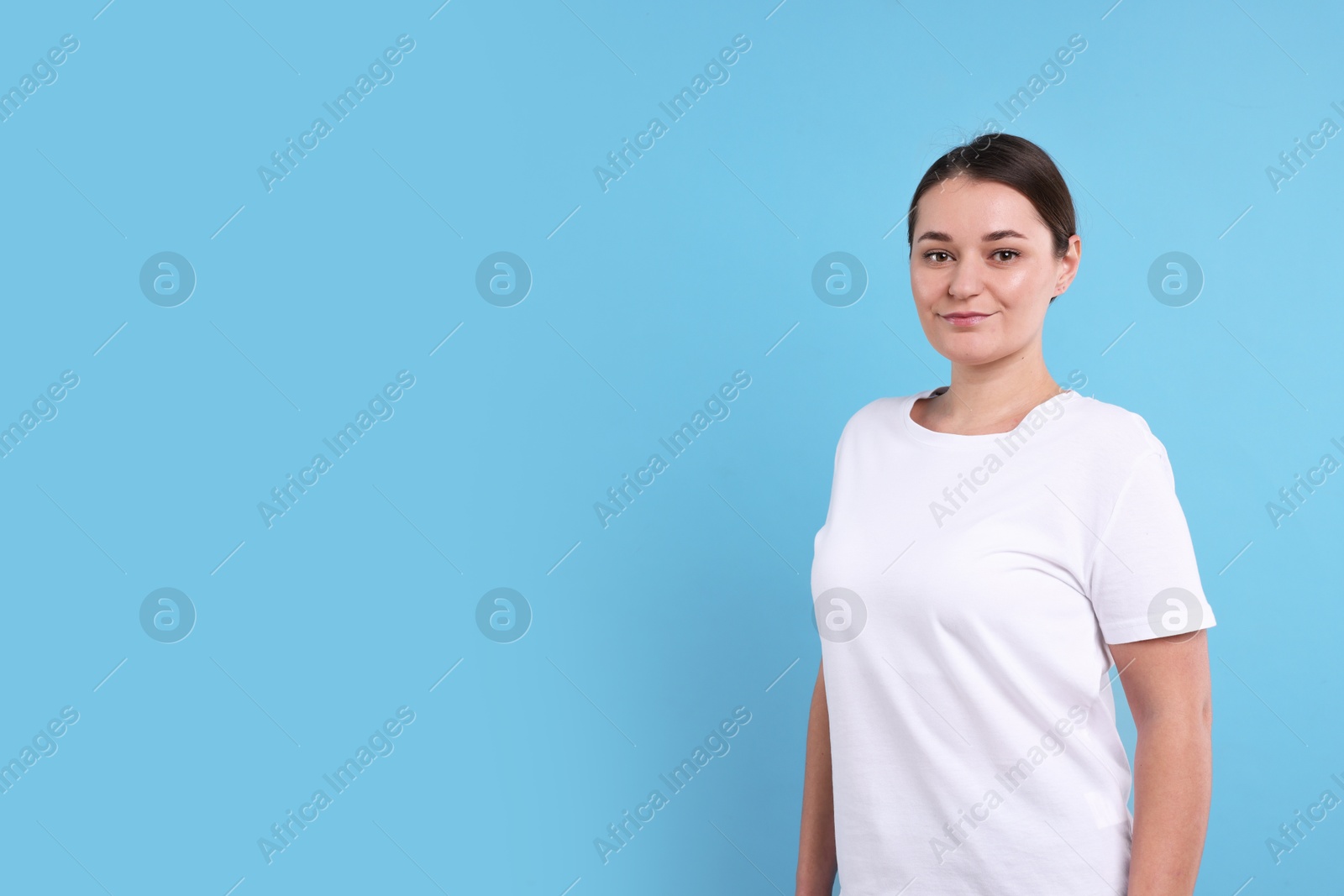 Photo of Woman in white t-shirt on light blue background. Mockup for design