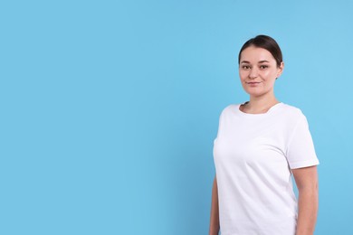 Photo of Woman in white t-shirt on light blue background. Mockup for design