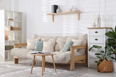 Photo of Beautiful sofa with cushions and coffee table in living room. Interior design